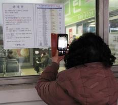 한 시민이 터미널에 붙은 버스 운행시간표를 찍고 있다 (사진=연합뉴스)